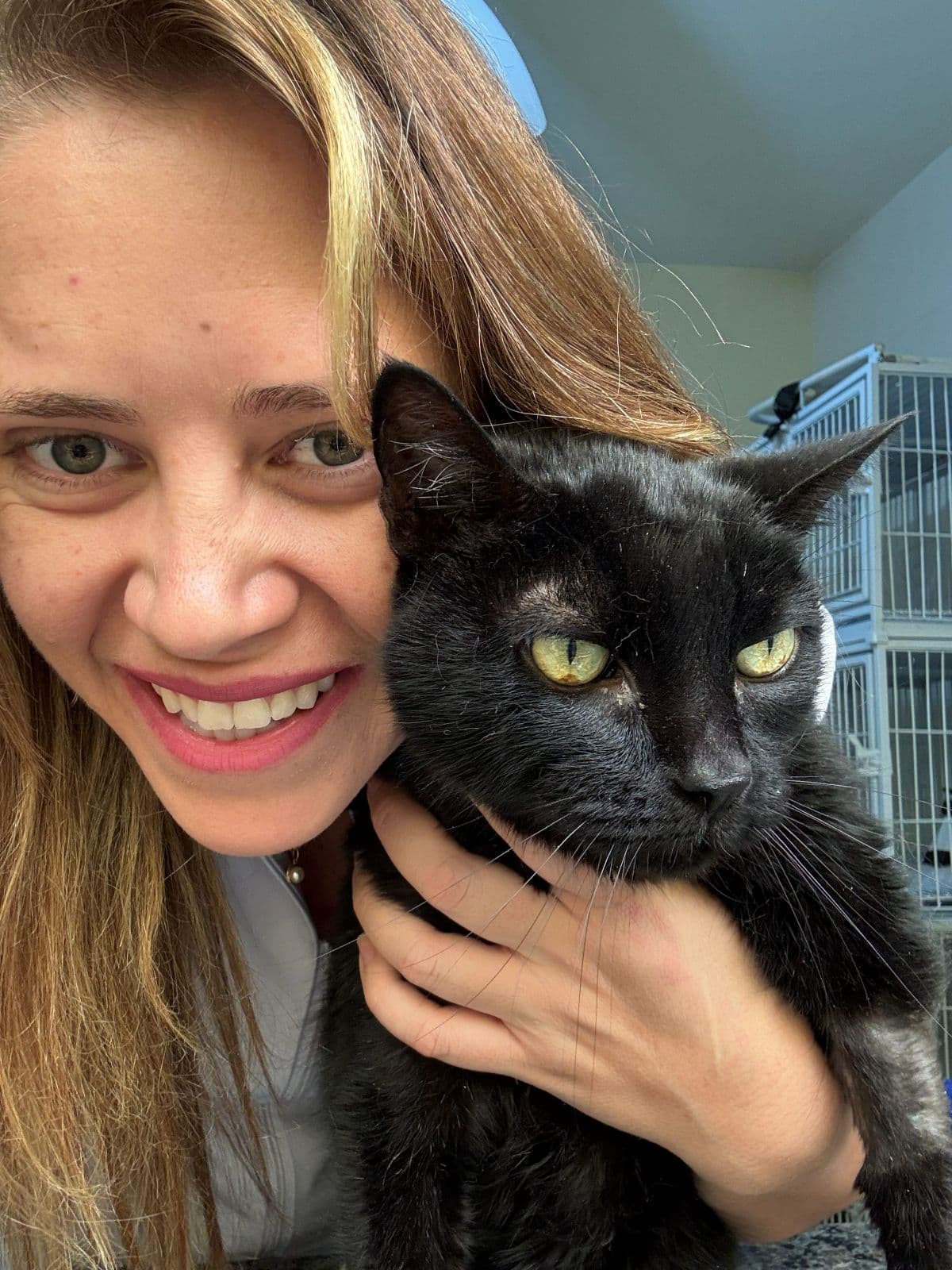 Profissional da Animal Care sorrindo com um gato preto no colo